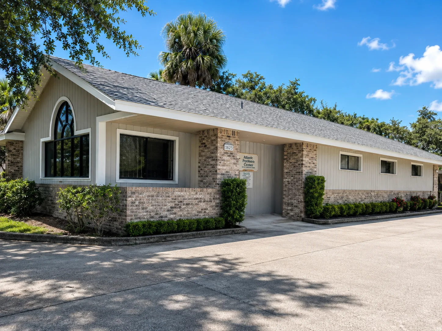 The exterior and entrance of our Palm Bay office, shaded by oaks and a palm
